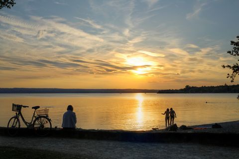 Frau sitzt neben ihrem Fahhrad am Ammersee