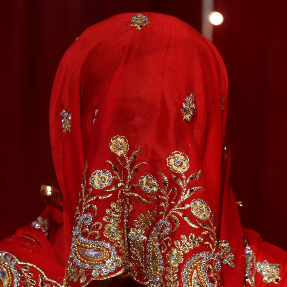 Eine indische Braut blickt durch ihren roten Schleier