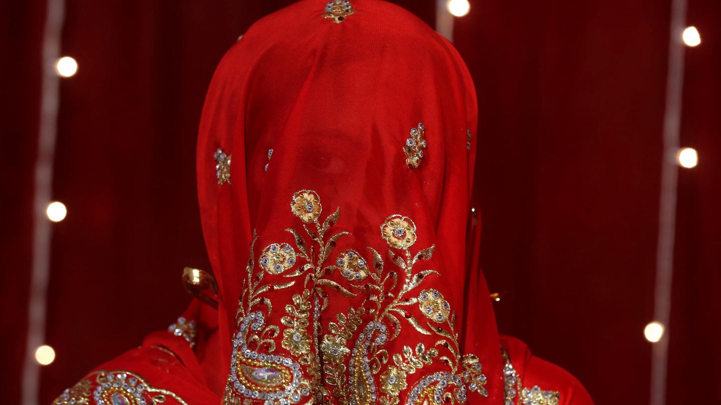 Eine indische Braut blickt durch ihren roten Schleier