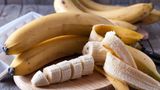 Bananen und Bananenscheiben auf einem Holzbrett