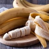 Bananen und Bananenscheiben auf einem Holzbrett