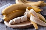 Bananen und Bananenscheiben auf einem Holzbrett
