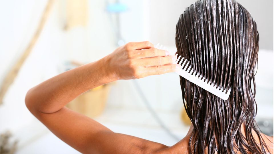 Frau gibt mit einem Kamm eine Haarpflege auf das Haar