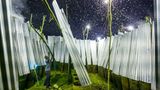 Ein Mann ersetzt eine Lampe in seiner Fanganlage. Wärme und Helligkeit locken die nachtfliegenden Insekten an. Daher werden die glühenden Spiralen von 400 Watt-Halogenlampen eingesetzt. Diese sind an mehrere Spulen angeschlossen, um ihre Leistung auf 1200 Watt pro Lampe zu steigern. Bei täglichem Betrieb hält ein solches Leuchtmittel nur etwa eine Woche lang. Der Stromverbrauch wird gezählt, wobei einige Anlagen auch illegal das Stromnetz anzapfen.