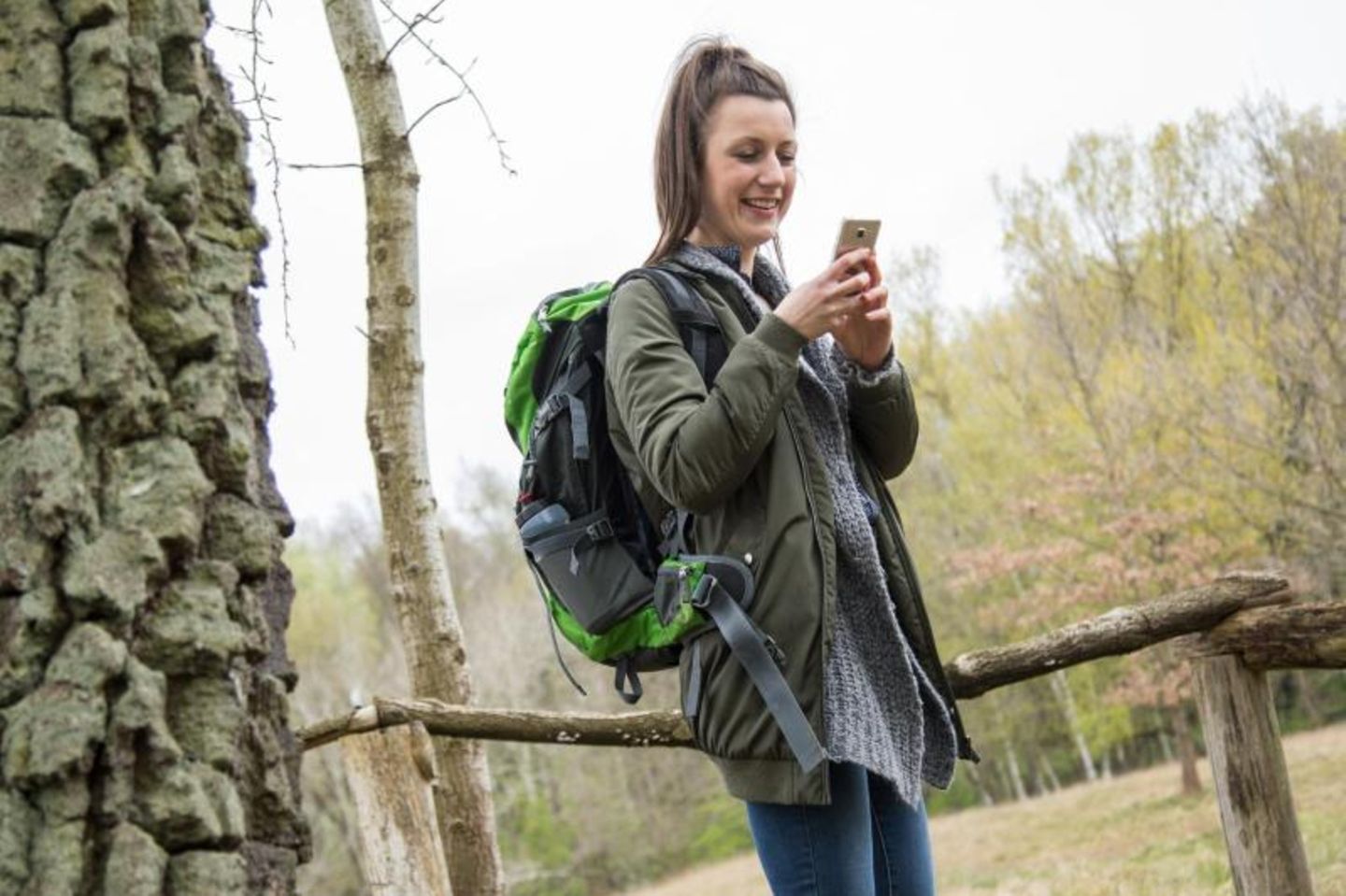 Frau schaut beim Wandern auf ihr Smartphone
