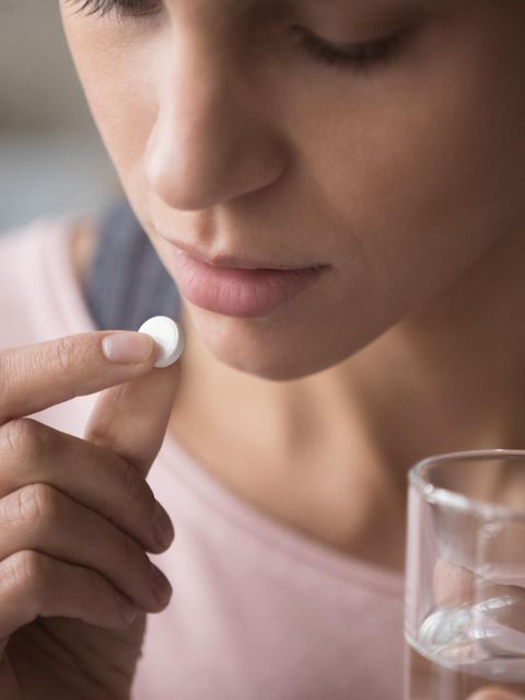 Junge Frau nimmt eine Pille mit einem Glas Wasser