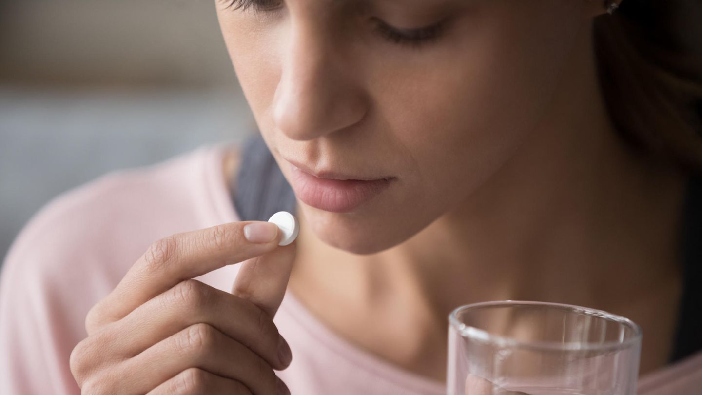 Junge Frau nimmt eine Pille mit einem Glas Wasser