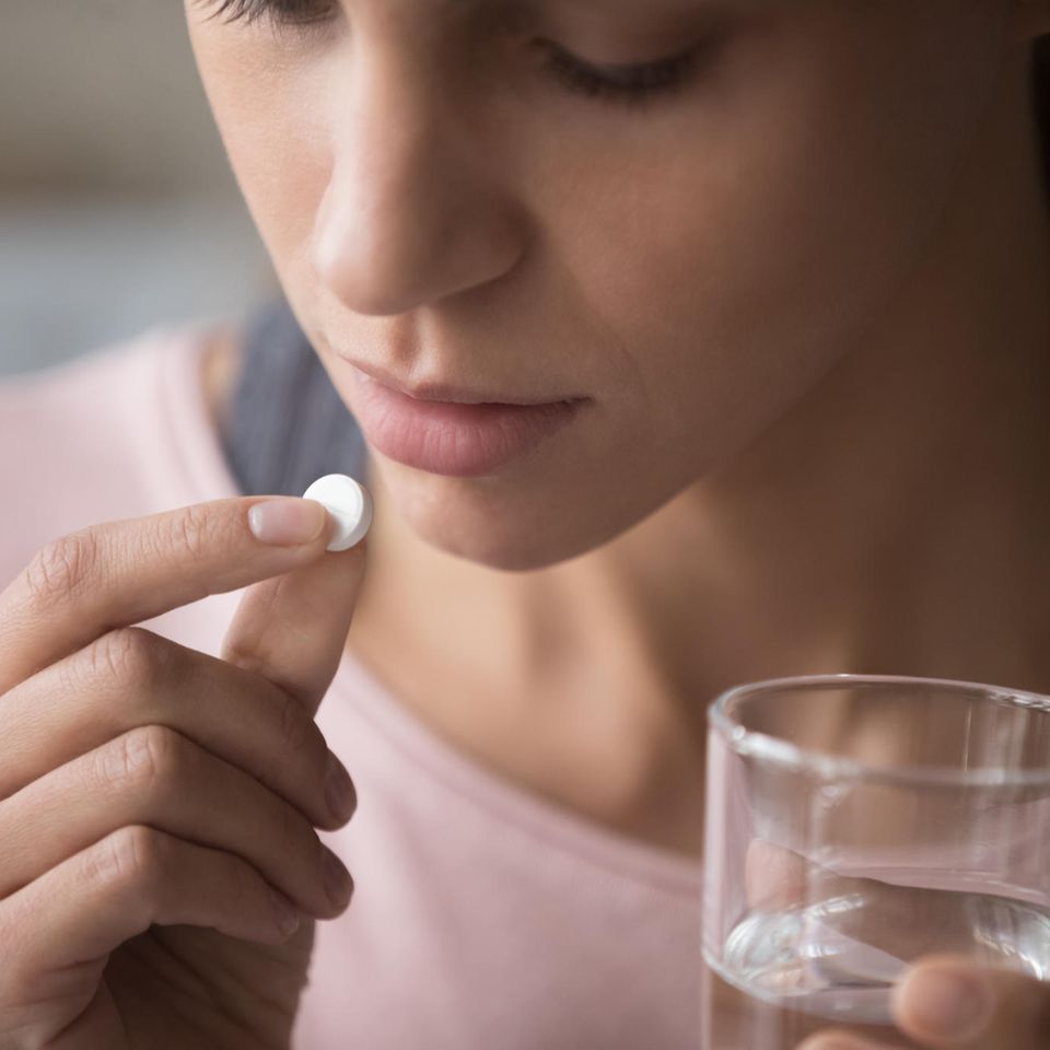 Junge Frau nimmt eine Pille mit einem Glas Wasser