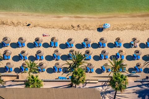 Luftbild von Sonnenliegen und Schirmchen am Strand