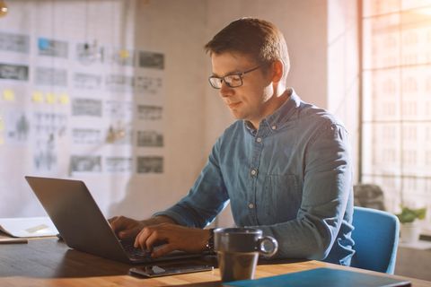 Mann sitzt im Homeoffice am Schreibtsich mit Laptop