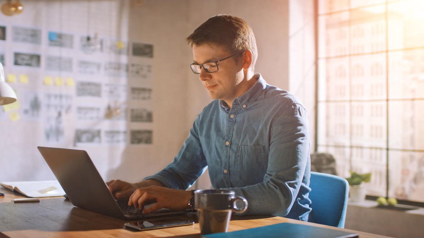 Mann sitzt im Homeoffice am Schreibtsich mit Laptop