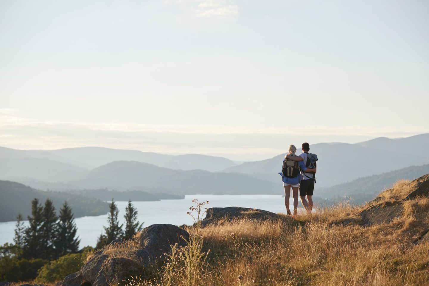 Ein Paar blickt beim Wandern vom Berg auf einen See