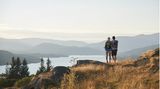 Ein Paar blickt beim Wandern vom Berg auf einen See