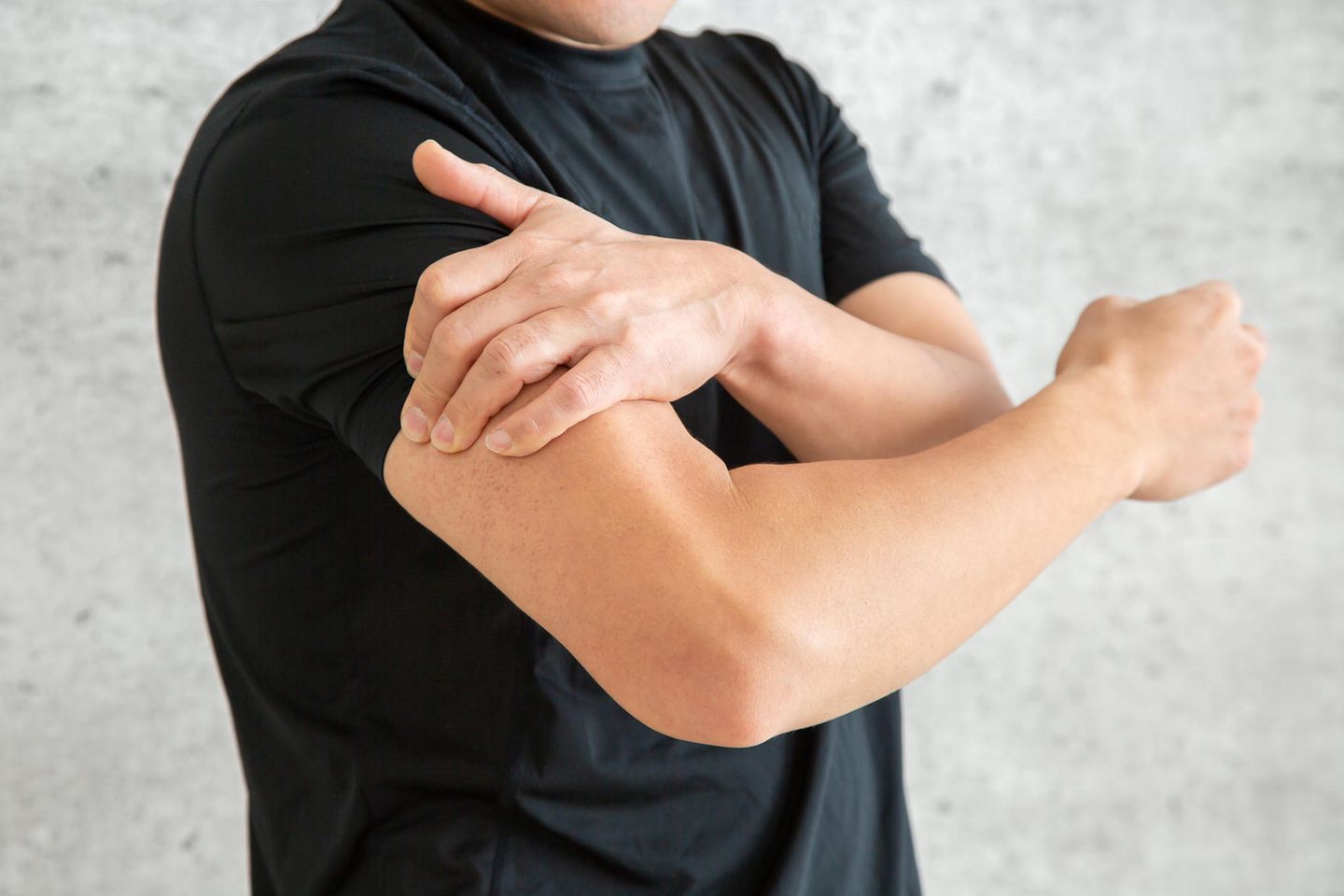 Mann mit Muskelkater hält den schmerzenden Oberarm