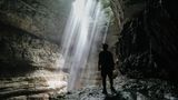 Wanderer in einer Höhle blickt in ein Loch in der Decke