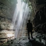 Wanderer in einer Höhle blickt in ein Loch in der Decke