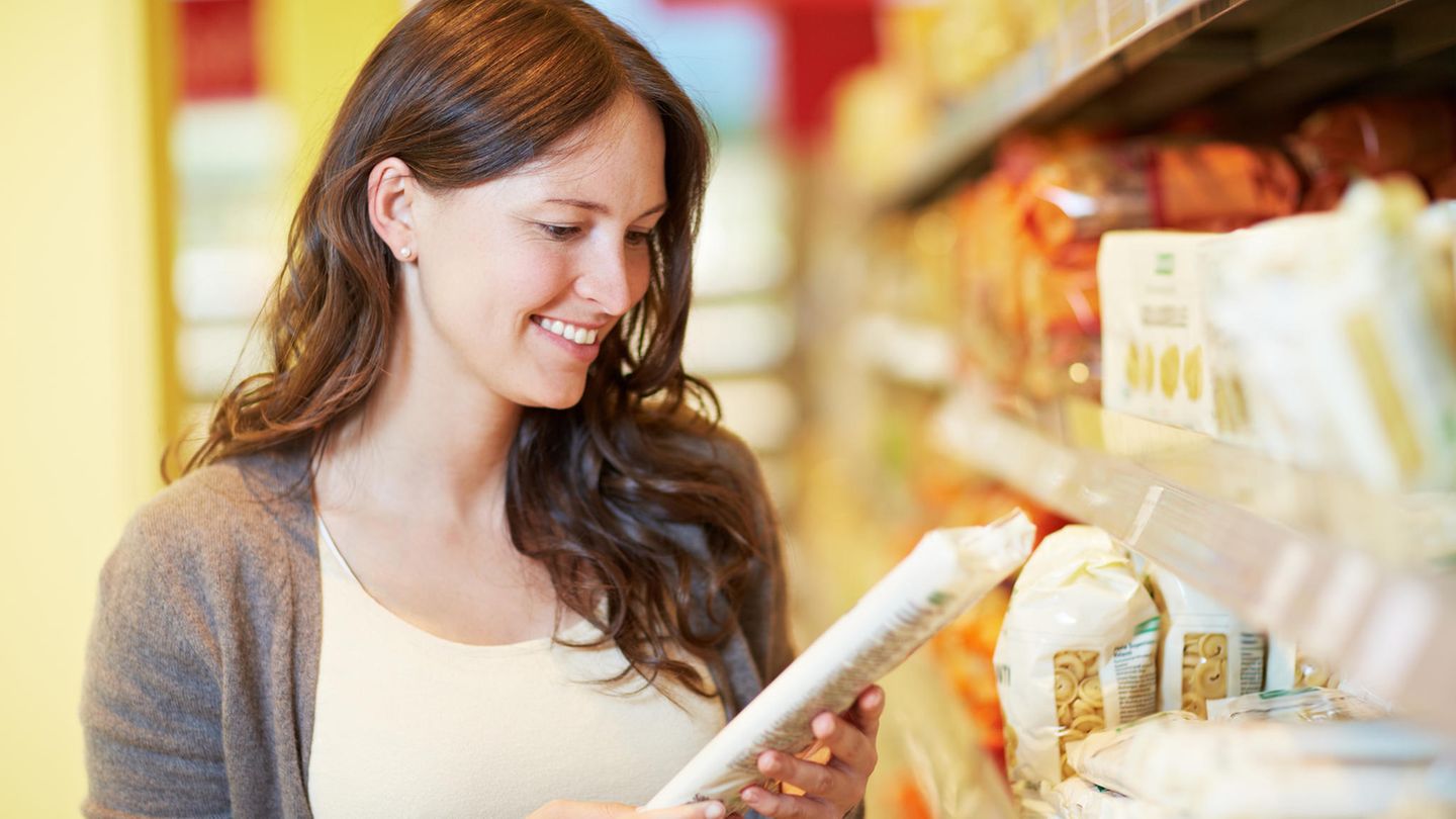 Frau mit Nudelpackung in der Hand im Supermarkt