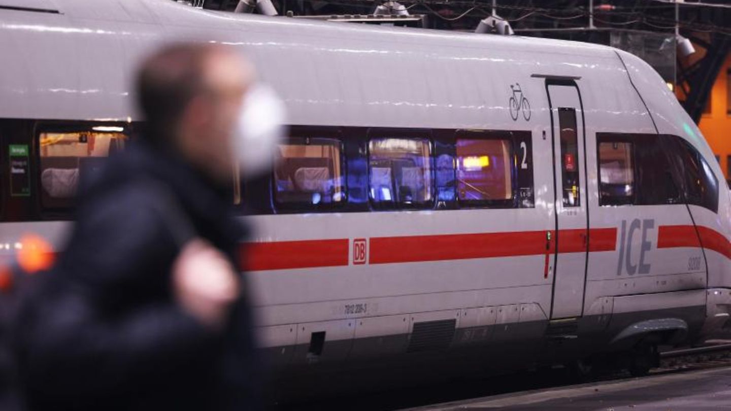 Mann  mit Maske vor einem Zug