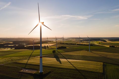 Windräder stehen während des Sonnenaufgangs auf einem Feld