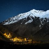 Mestia beleuchtet vor einem großen Berg