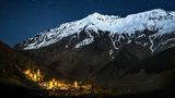 Mestia beleuchtet vor einem großen Berg