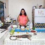 Maria Luz Fedric  Leguan mit Reis und Bohnen (Rezept siehe unten)      Sie wuchs auf einer honduranischen Insel auf, heute lebt Maria Luz Fedric mit ihrem Mann auf den Cayman Islands, dort führte die 53-Jährige lange ein Fischrestaurant. Damit ihre Enkel ihre honduranischen Wurzeln nicht vergessen, kocht sie den beiden gern dieses Festgericht: Leguan mit Reis und Bohnen Honduras  Wie man einen Leguan küchenfertig zubereitet, sollten Sie sich von Frau Fedric erklären lassen (in Europa wäre jedenfalls Kaninchen eine gangbare Alternative).      Das gehackte Gemüse (grob: grüne Paprika, Sellerie, fein: Knoblauch, scharfe und süße Chilies) und das grob zerteilte Fleisch getrennt zurückhaltend würzen: Frau Fedric benutzt Liquid Aminos, eine salzarme Sojasoßen-Variante. Das Gemüse in einer tiefen Pfanne andünsten, das Fleisch dazulegen und anbraten. Thymian dazu, Deckel drauf und 30 Minuten schmurgeln lassen, schließlich Kokosmilch hinzufügen und alles in weiteren15 Minuten garziehen lassen. Bohnen und Reis in Kokosmilch garen. Dick und längs geschnittene Kochbananen goldbraun braten und alles servieren. Buen provecho!