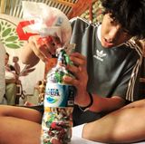 Die Bewohnerinnen und Bewohner stopfen den Abfall in Plastikflaschen.