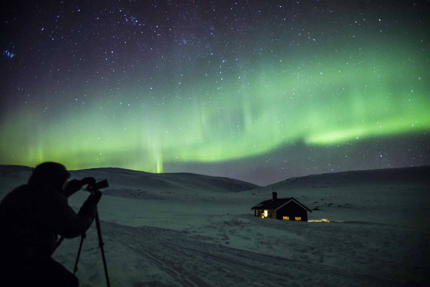Mann fotografiert Nordlichter am Himmel über dem Dovrefjell-Sunndalsfjella-Nationalpark