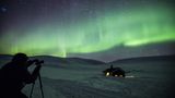 Mann fotografiert Nordlichter am Himmel über dem Dovrefjell-Sunndalsfjella-Nationalpark