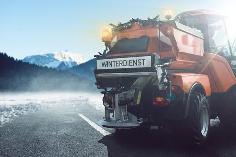 Winterdienst-Fahrzeug auf der Straße im Winter mit Schnee im Hintergrund