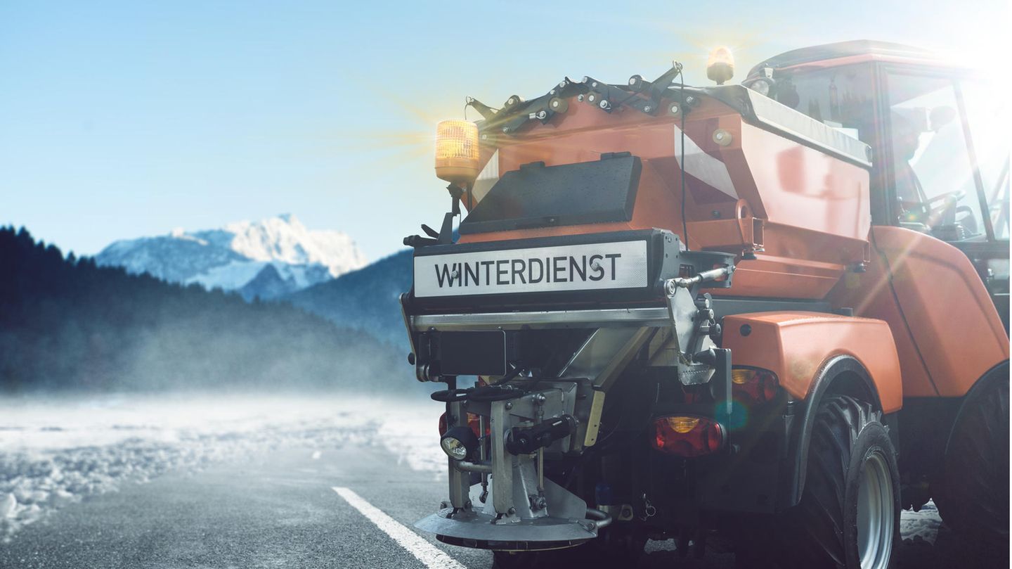 Winterdienst-Fahrzeug auf der Straße im Winter mit Schnee im Hintergrund