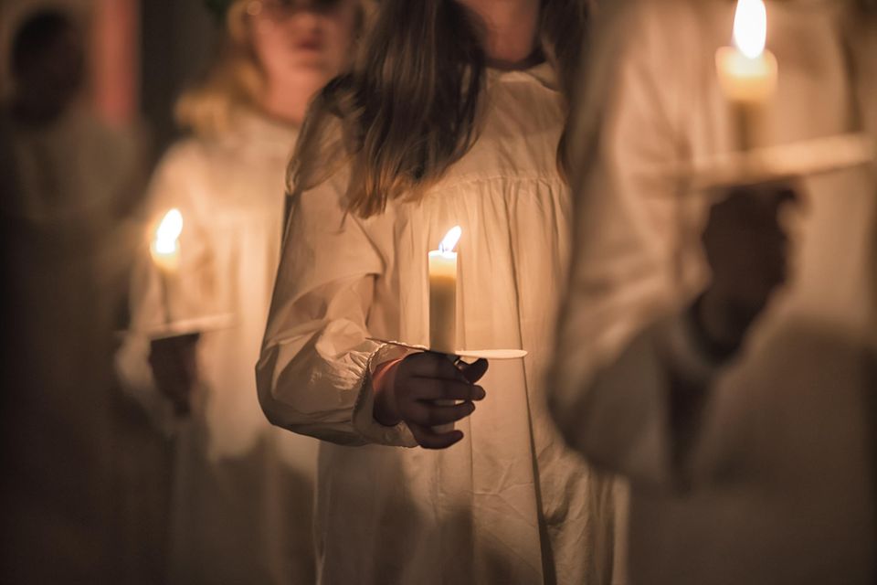 Mädchen tragen Kerzen zum Luciafest in Schweden