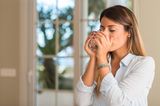 Frau trinkt eilig ein Glas Wasser, weil sie Durst hat