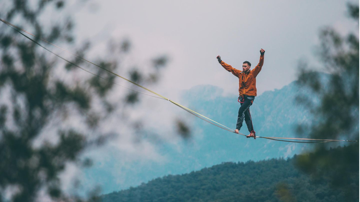 Mann balanciert auf einer Slackline in großer Höhe