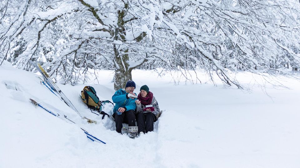 Rainer Waelder Winterwantern Schwarzwald, FINAL bearbeitete Dateien für Litho, 14.10.2021; Skilangläufer machen Picknick im Schnee im Schwarzwald auf dem Fernskiwanderweg von Schonach zum Belchen Unter dem eisverkrusteten Baum gibt's Heißes: Tee vom Kocher