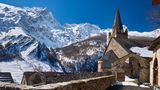 Kirche in La Grave mit Alpen und Gipfel des La Meije im Hintergrund im Winter