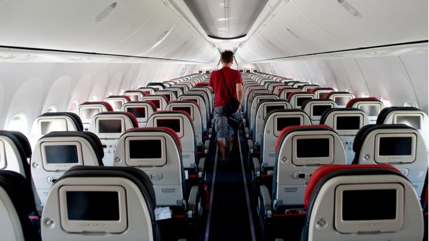 Ein Mann läuft durch ein sonst leeres Flugzeug
