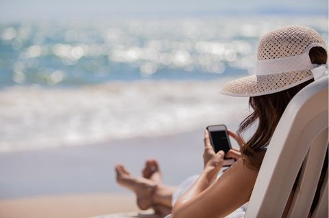 Frau mit Handy am Strand