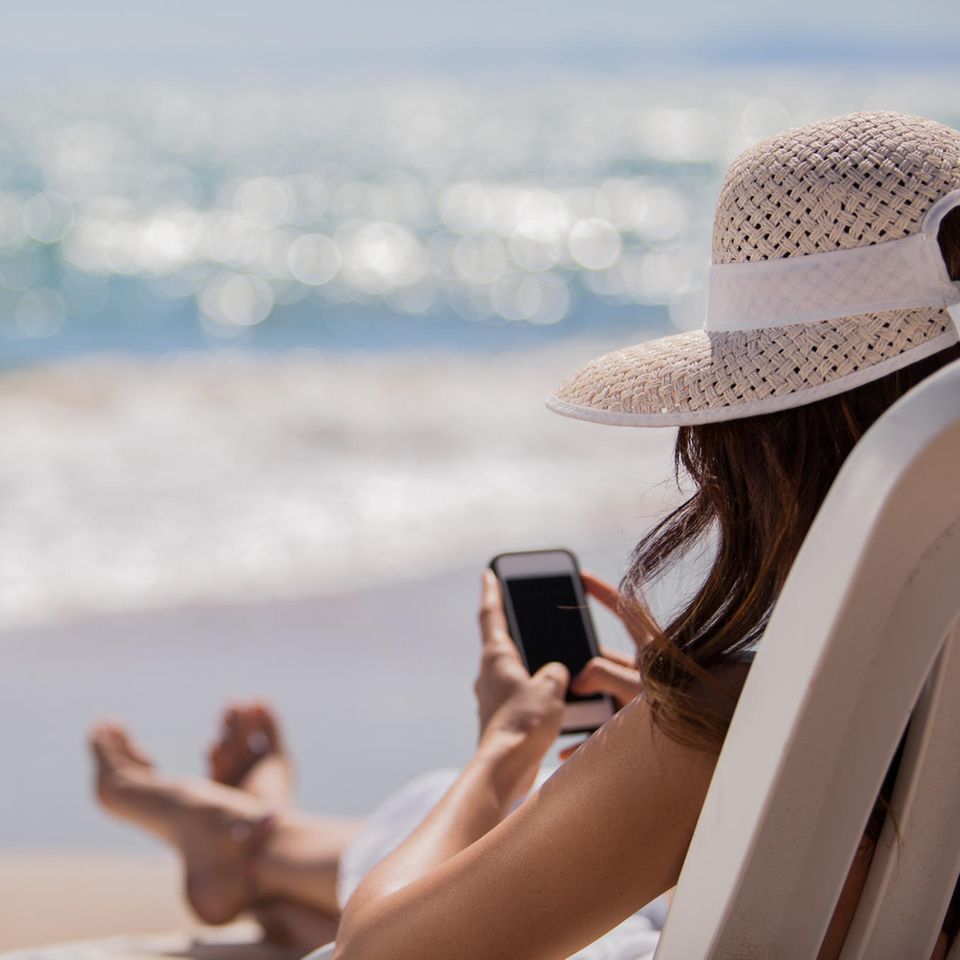 Frau mit Handy am Strand