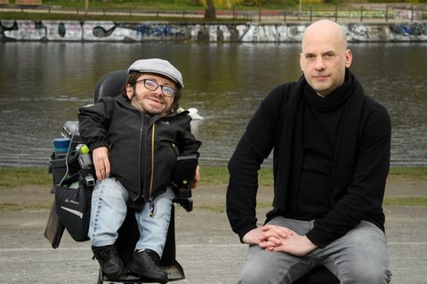 Raúl Krauthausen und Benjamin Schwarz sitzen vor einem Fluss