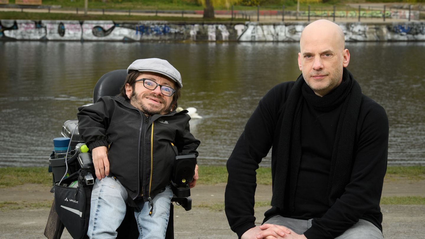 Raúl Krauthausen und Benjamin Schwarz sitzen vor einem Fluss