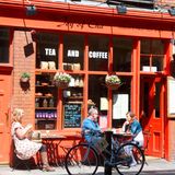 Menschen sitzen in Dublin vor einem Café in der Sonne