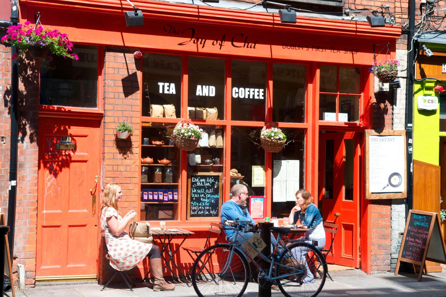 Menschen sitzen in Dublin vor einem Café in der Sonne