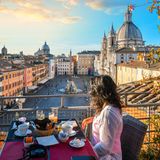 Frau genießt die Sonne in einem Café in Rom mit Blick auf den Petersdom