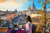 Frau genießt die Sonne in einem Café in Rom mit Blick auf den Petersdom