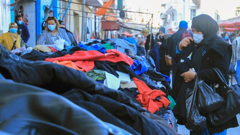 Eine Frau schaut sich Altkleider auf einem Markt an