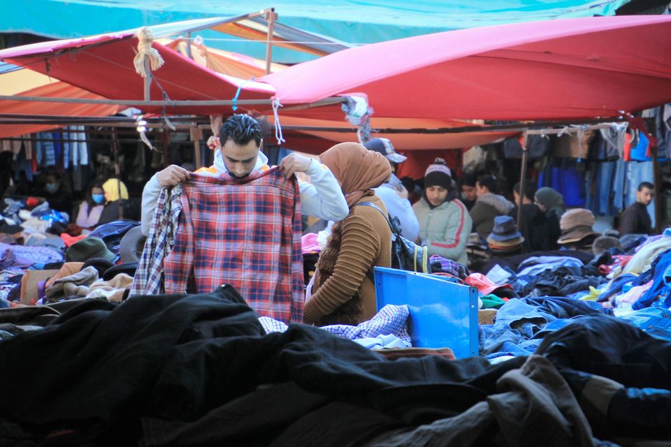 Ein Kunde schaut sich gebrauchte Kleidungsstücke auf einem Markt in Tunis an.