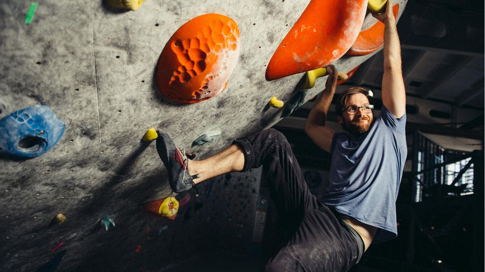 Ein Mann bouldert im Überhang und lächelt dabei. Ein Mann bouldert im Überhang und lächelt dabei.