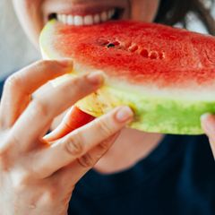 Junge Frau beißt in ein Stück Wassermelone