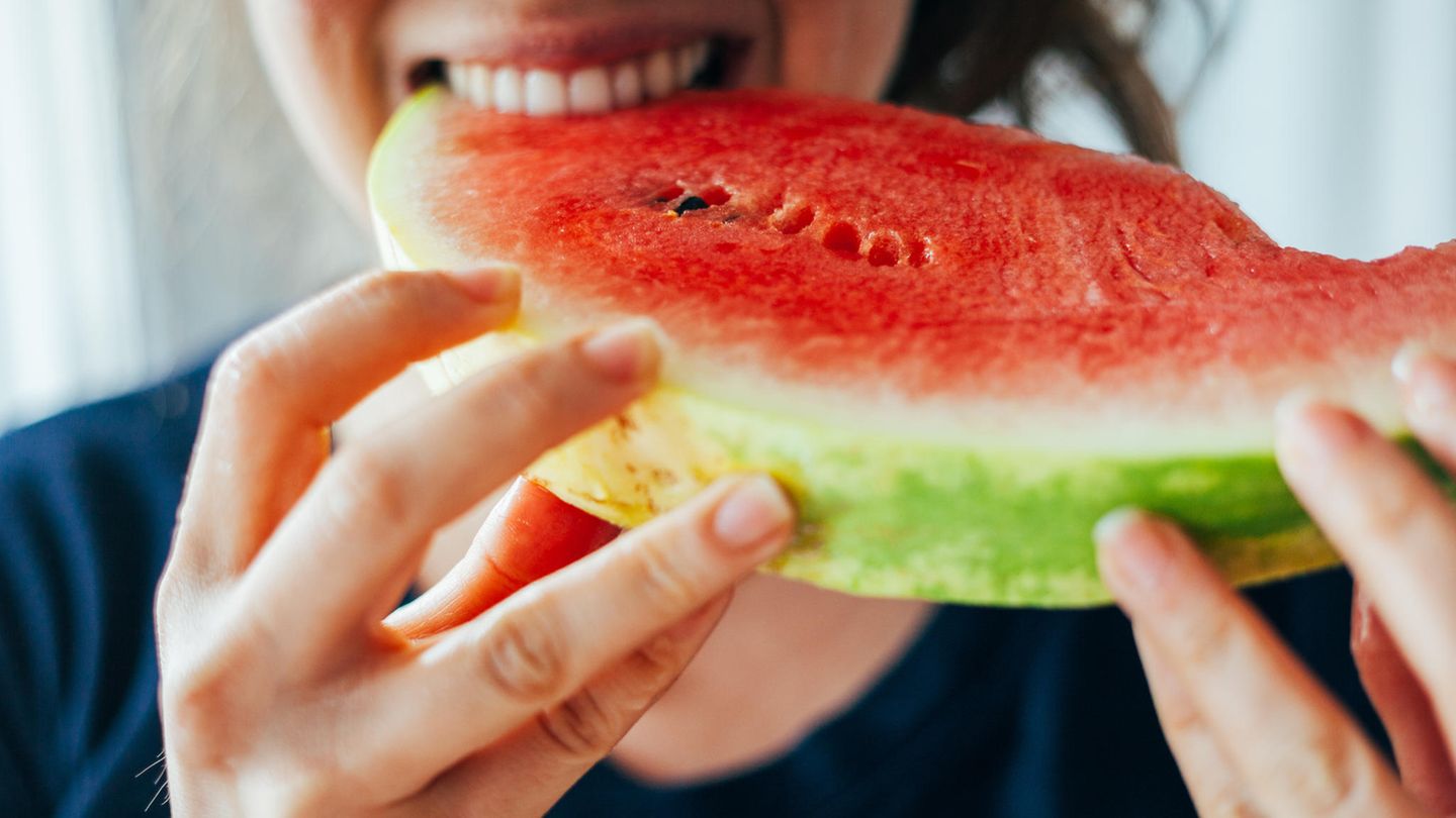 Wassermelone: 6,2 g Zucker und 38 kcal Junge Frau beißt in ein Stück Wassermelone